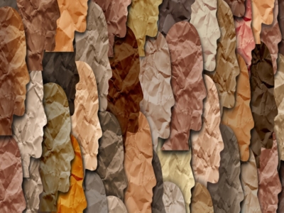 Collage of overlapping paper silhouettes of human profiles in various shades of brown, beige, and tan, creating a textured pattern.