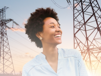 A person standing outdoors near large electrical transmission towers at sunset, with power lines stretching across the sky.