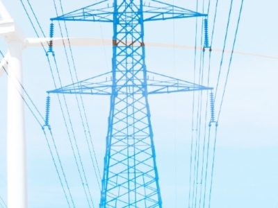 Tall electrical transmission towers with multiple power lines alongside a large white wind turbine under a clear blue sky.