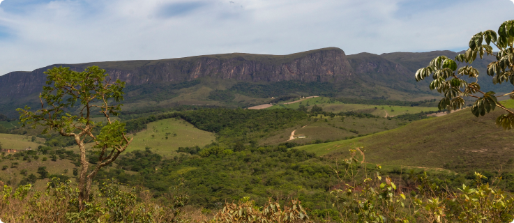 Paisagem da Serra da Canastra com vegetação nativa preservada, céu parcialmente nublado e áreas verdes do cerrado.