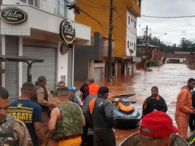 Equipe de resgate auxilia moradores em rua inundada com jet ski e caixas de suprimentos em Juiz de Fora.