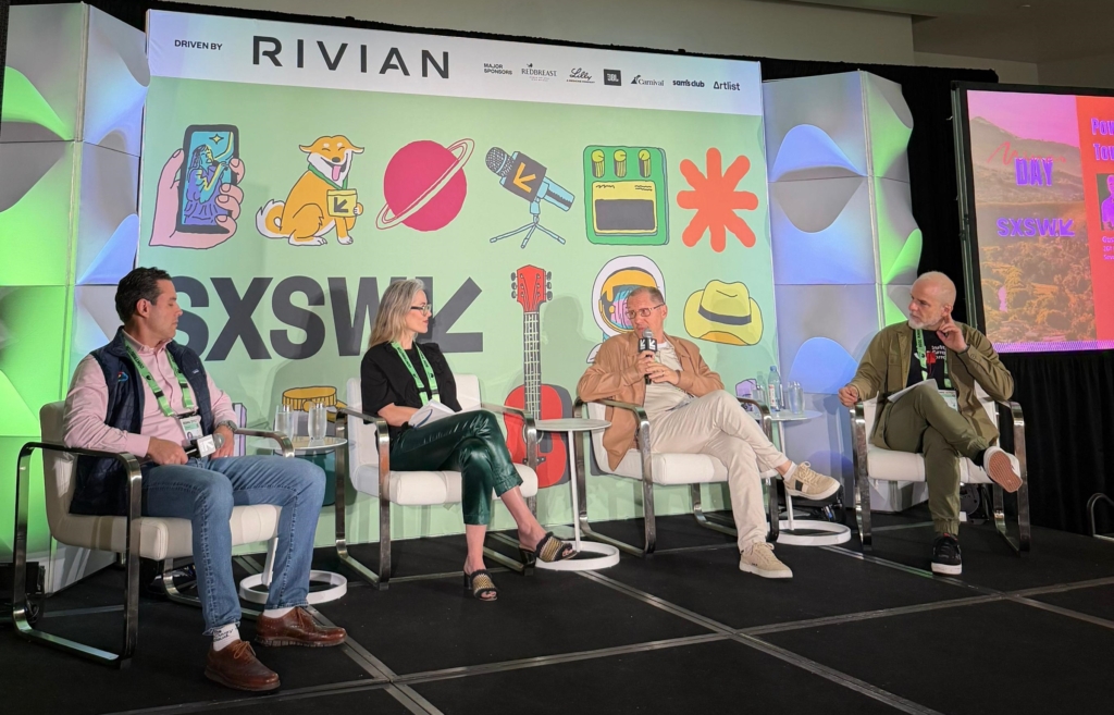  Quatro pessoas estão sentadas em poltronas brancas modernas, conversando em um ambiente profissional e criativo. 