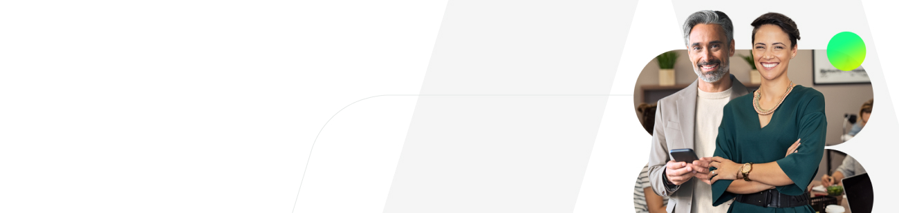 Dois profissionais sorridentes — um homem e uma mulher — estão em destaque dentro de uma moldura arredondada. O homem, à esquerda, tem cabelos e barba grisalhos e segura um smartphone. A mulher, à direita, tem cabelos curtos e escuros, usa um vestido verde-escuro, colar colorido e está com os braços cruzados. Ao fundo deles, nota-se um ambiente de escritório compartilhado.